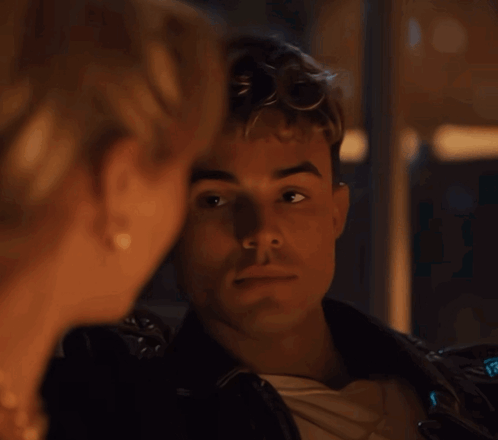 A Man And A Woman Are Looking At Each Other And The Man Is Wearing A Leather Jacket GIF