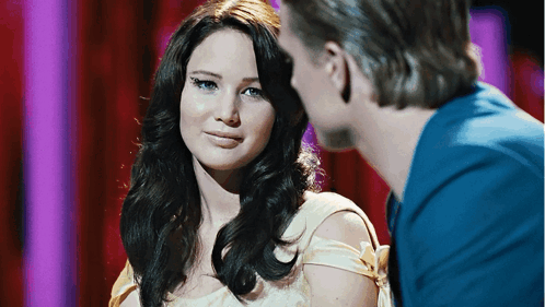 A Man And A Woman Are Looking At Each Other And The Woman Is Wearing A White Dress GIF