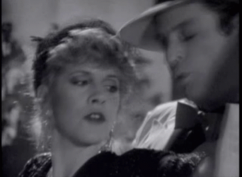 A Man And A Woman Are Looking At Each Other In A Black And White Photo GIF