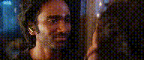 A Man And A Woman Are Looking At Each Other In A Dark Room . GIF