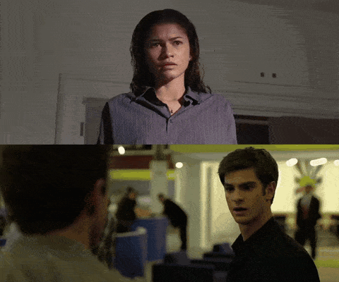 A Man And A Woman Are Looking At Each Other In A Dark Room GIF