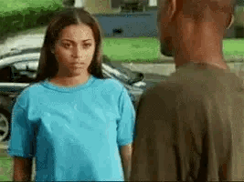A Man And A Woman Are Looking At Each Other In Front Of A Car . GIF
