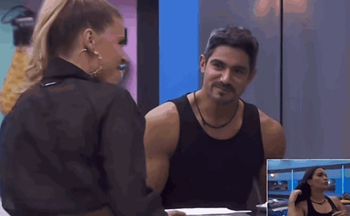 A Man And A Woman Are Looking At Each Other In Front Of A Mirror GIF