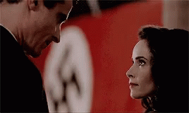 a man and a woman are looking at each other in front of a nazi flag .