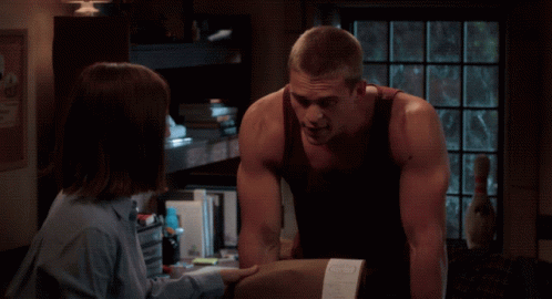 A Man And A Woman Are Looking At Each Other In Front Of A Texas Poster GIF