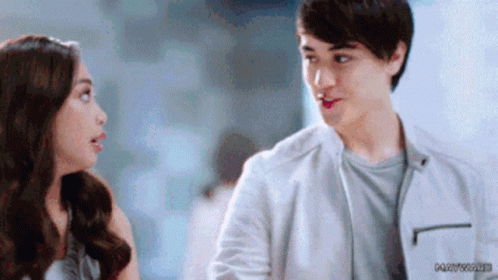 A Man And A Woman Are Looking At Each Other . The Man Is Wearing A White Jacket . GIF