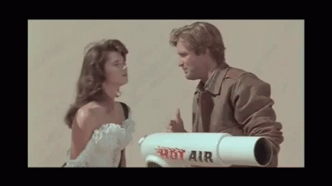 a man and a woman are looking at each other while a man holds a rot air rocket .