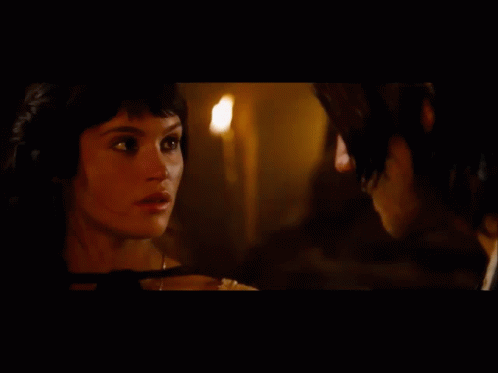 A Man And A Woman Are Looking At Each Other With A Mountain In The Background GIF