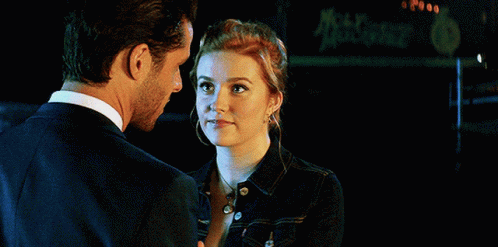 a man and a woman are looking at each other with a sign in the background that says mccafe