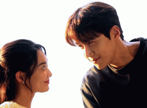 A Man And A Woman Are Looking At Each Other With A White Background GIF