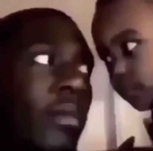 A Man And A Woman Are Looking At Each Other With Their Eyes Wide Open . GIF