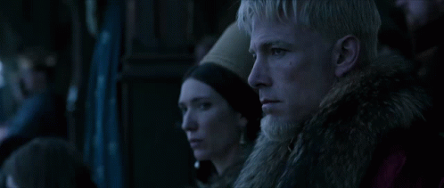 A Man And A Woman Are Looking At Something In A Dark Room GIF