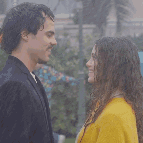 A Man And A Woman Are Looking Into Each Other 'S Eyes And The Woman Is Wearing A Yellow Sweater GIF