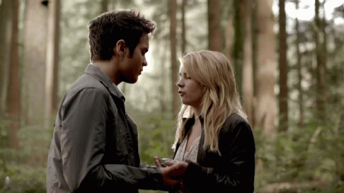 A Man And A Woman Are Looking Into Each Other 'S Eyes In A Forest GIF