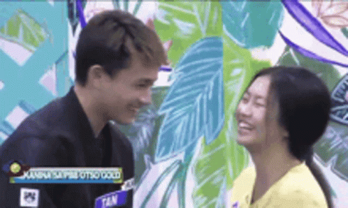 A Man And A Woman Are Looking Into Each Other 'S Eyes In Front Of A Mural . GIF