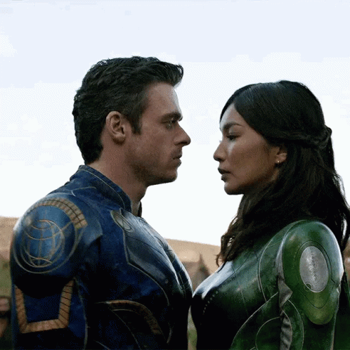 A Man And A Woman Are Looking Into Each Other 'S Eyes . The Woman Is Wearing A Green Suit . GIF