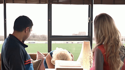 A Man And A Woman Are Looking Out Of A Window GIF