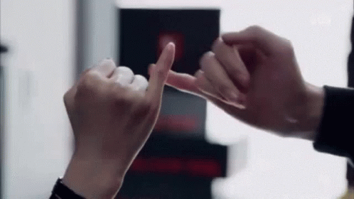 A Man And A Woman Are Making A Pinkie Promise With Their Fingers . GIF