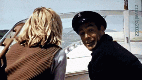 A Man And A Woman Are On A Boat With A Sign That Says Cristallo2022 On It GIF
