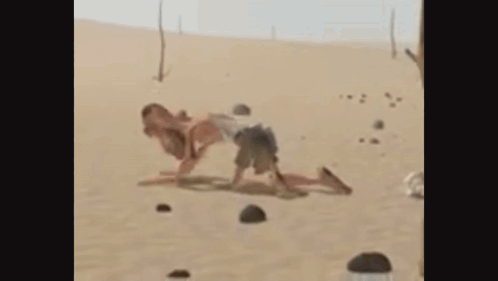 A Man And A Woman Are Playing In The Sand . GIF