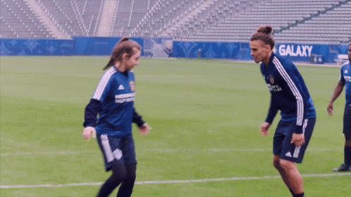 A Man And A Woman Are Playing Soccer And The Woman Is Wearing A Shirt That Says Herbalife On It GIF