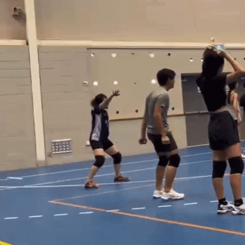 A Man And A Woman Are Playing Volleyball On A Blue Court GIF