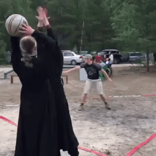 A Man And A Woman Are Playing Volleyball On A Dirt Court GIF