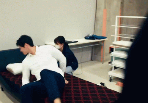 A Man And A Woman Are Playing With Pillows On A Couch In A Room GIF