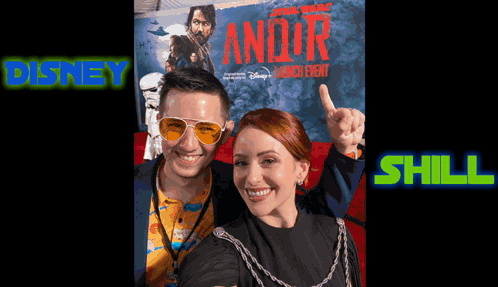 A Man And A Woman Are Posing For A Photo In Front Of A Star Wars Poster GIF
