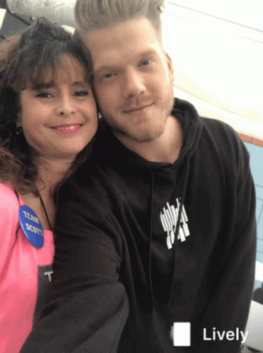 A Man And A Woman Are Posing For A Picture And The Man Is Wearing A Black Hoodie With The Word Scott On It GIF