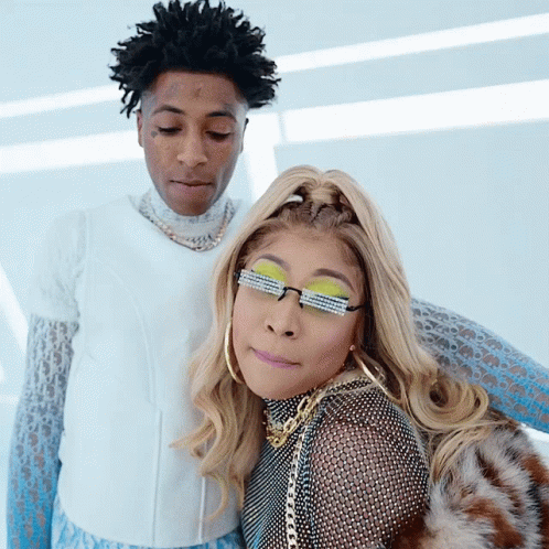 A Man And A Woman Are Posing For A Picture And The Woman Has Sunglasses On Her Eyes GIF
