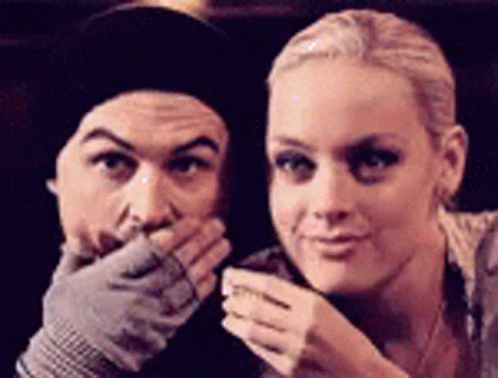 A Man And A Woman Are Posing For A Picture And The Woman Is Covering Her Mouth With Her Hand . GIF