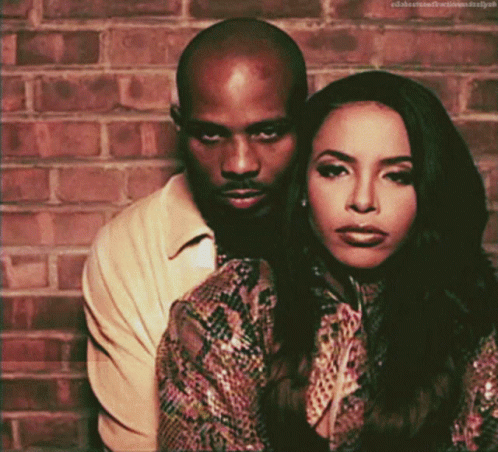 A Man And A Woman Are Posing For A Picture And The Woman Is Wearing A Snake Print Top GIF