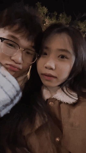 A Man And A Woman Are Posing For A Picture And The Woman Is Wearing Glasses GIF