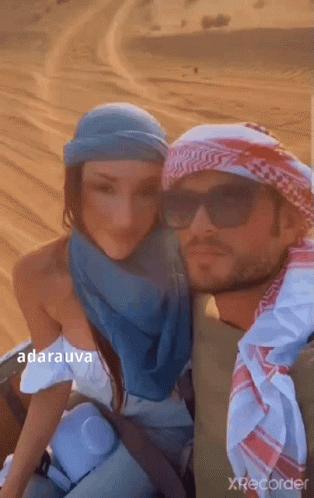A Man And A Woman Are Posing For A Picture In A Desert . GIF