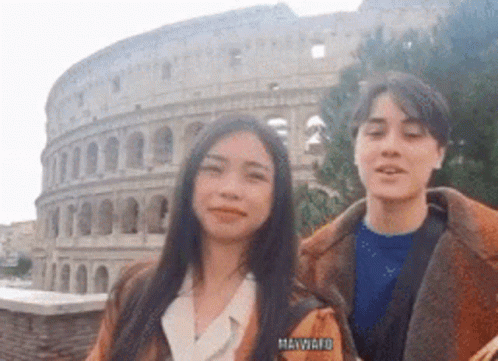 A Man And A Woman Are Posing For A Picture In Front Of The Colosseum In Rome . GIF