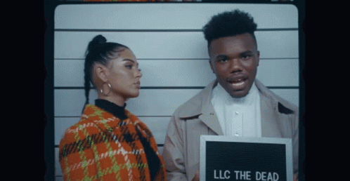A Man And A Woman Are Posing For A Picture With A Sign That Says Llc The Dead GIF