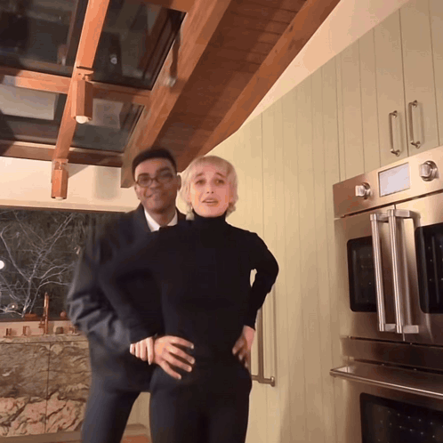 A Man And A Woman Are Posing In A Kitchen GIF