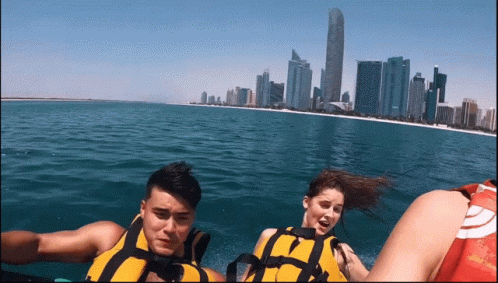 A Man And A Woman Are Riding A Boat In The Ocean GIF