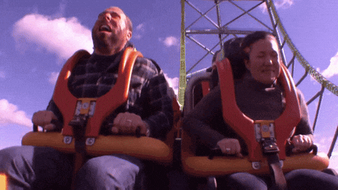 A Man And A Woman Are Riding A Roller Coaster With The Letter G On The Front GIF