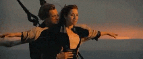 A Man And A Woman Are Riding On The Back Of A Boat . GIF