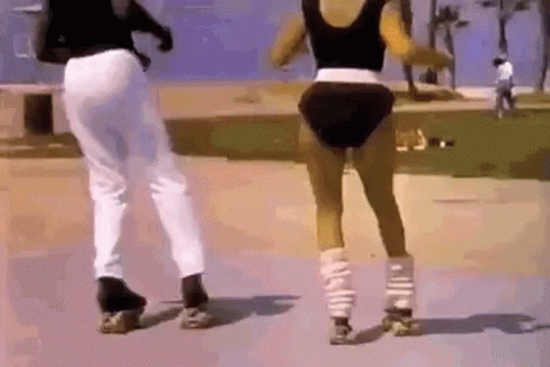 A Man And A Woman Are Rollerblading On A Sidewalk . GIF
