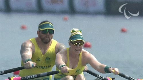 A Man And A Woman Are Rowing In A Boat That Says Australia On The Front GIF