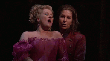 A Man And A Woman Are Singing On A Stage . GIF
