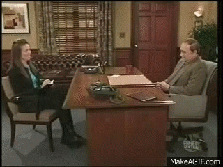 A Man And A Woman Are Sitting At A Desk And Talking To Each Other . GIF