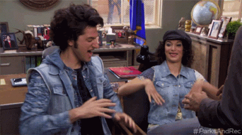 A Man And A Woman Are Sitting At A Desk With The Hashtag #Parksandrec On The Bottom Right GIF