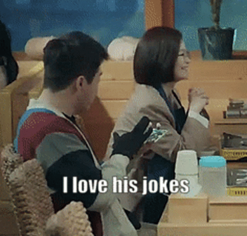 A Man And A Woman Are Sitting At A Table And The Man Is Saying I Love His Jokes GIF