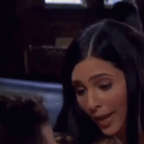 A Man And A Woman Are Sitting At A Table And The Woman Is Touching The Man 'S Neck . GIF