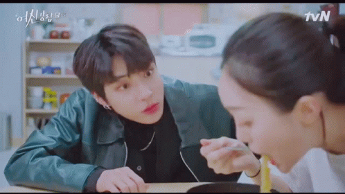 A Man And A Woman Are Sitting At A Table Eating Food Together . GIF
