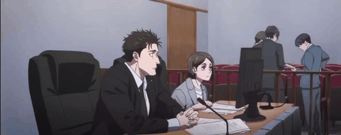 A Man And A Woman Are Sitting At A Table In A Courtroom GIF